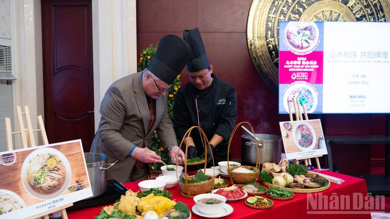 International friends experience how a bowl of pho is prepared. (Photo: NDO)