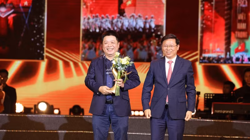 Que Dinh Nguyen, Deputy Editor-in-Chief of Nhan Dan Newspaper (L) representing the organising board of the ‘Homeland in Our Hearts’ concert, receives the Devotion insignia from Tran Thanh Lam, Party Central Committee member and Deputy Head of the Party Central Committee’s Commission for Information, Education and Mass Mobilisation.