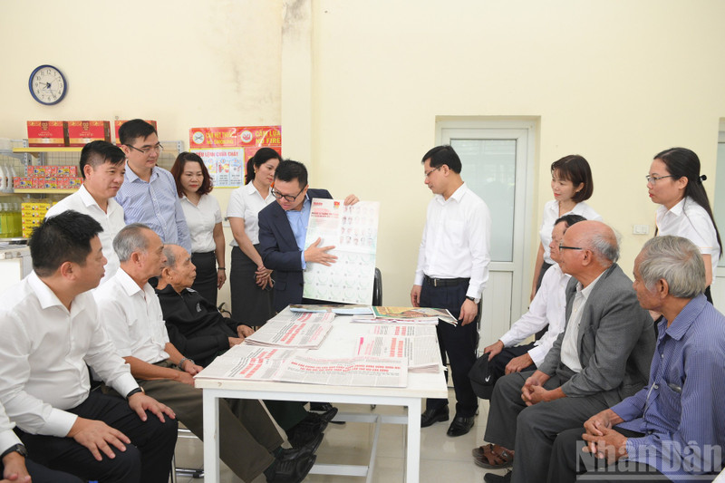 Le Quoc Minh, Editor-in-Chief of Nhan Dan Newspaper, presents the special supplement on the Draft Documents for the 14th National Party Congress to residents at the post office in Da Trach Commune, Hung Yen Province. (Photo: The Dai)