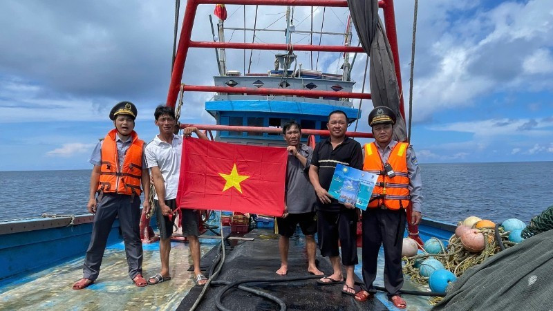 Fishery surveillance officials distribute leaflets on maritime sovereignty and present flags to fishermen at sea.
