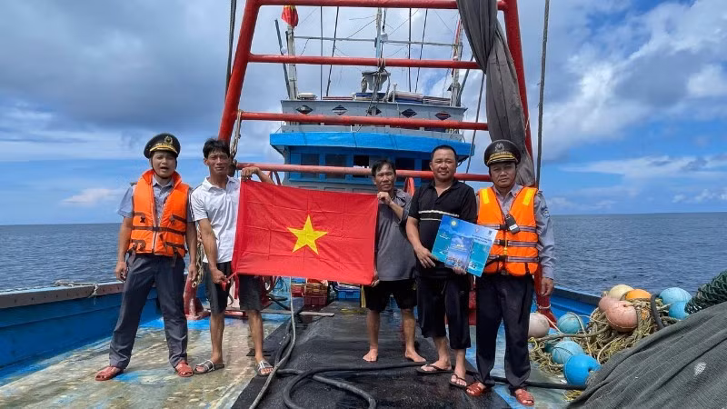 Fishery surveillance officials distribute leaflets on maritime sovereignty and present flags to fishermen at sea.