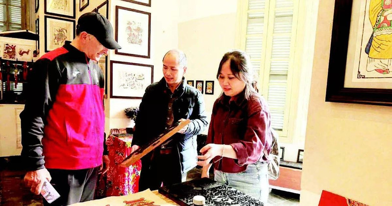 Vo Ca Dao guides foreign visitors in experiencing woodblock printing.