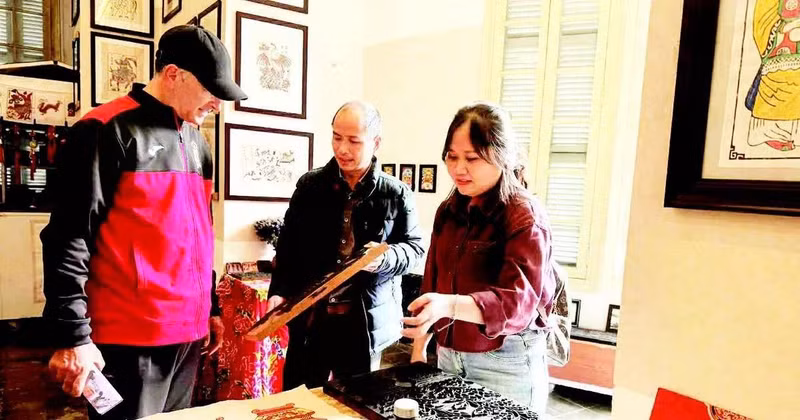 Vo Ca Dao guides foreign visitors in experiencing woodblock printing.