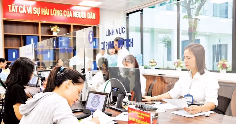 People carry out administrative procedures with staff at the one-stop service section of Dong Da Ward, Ha Noi. (Photo: THE DAI)