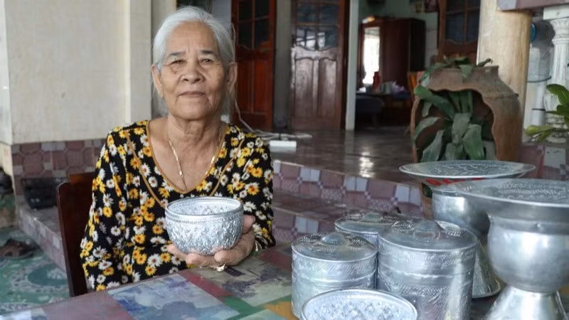 Artisan Dang Thi My Tram (Bau Truc Hamlet, Ninh Phuoc Commune, Khanh Hoa Province) alongside traditional handcrafted silver-engraved products of the Cham community. (Photo: NGUYEN TRUNG)