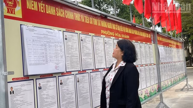Voters in Hoa Khanh ward read information on the public notice board.