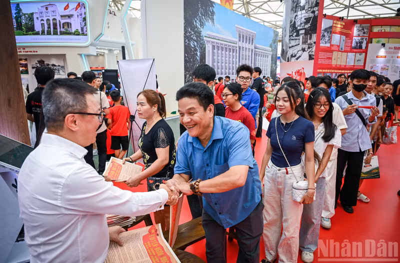 The joy of a small family as they queue to receive the special Nhan Dan supplement. (Photo: Thanh Dat)