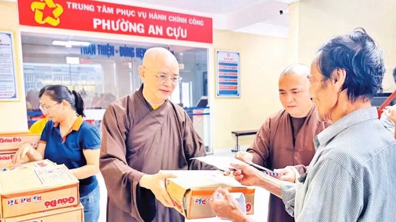 Venerable Thich Hue Phuoc (left) presents support gifts to people affected by flooding in An Cuu Ward, Hue City.