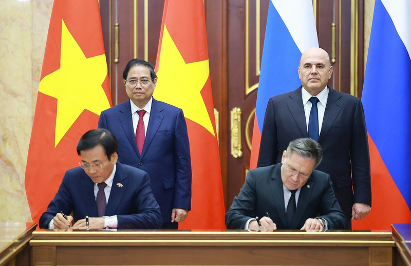 Vietnamese PM Pham Minh Chinh (standing, left) and his Russian counterpart Mikhail Mishustin (standing, right) witness the signing of the agreement between the two governments on cooperation in building a nuclear power plant on the territory of Viet Nam. (Photo: VNA)