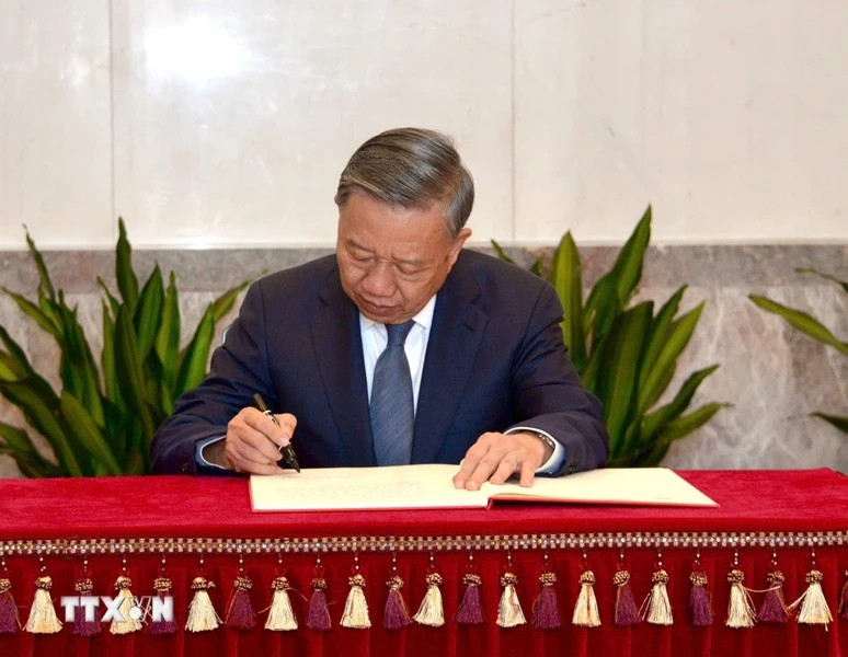 General Secretary and President To Lam writes in the guest book at the memorial house.