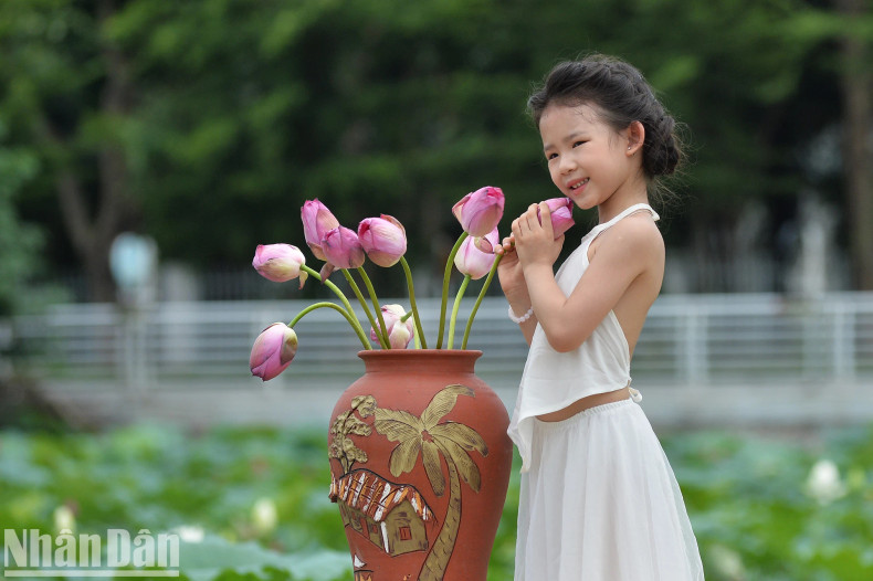 Six-year-old Ha Linh from Ba Dinh District poses for photos with lotus flowers.