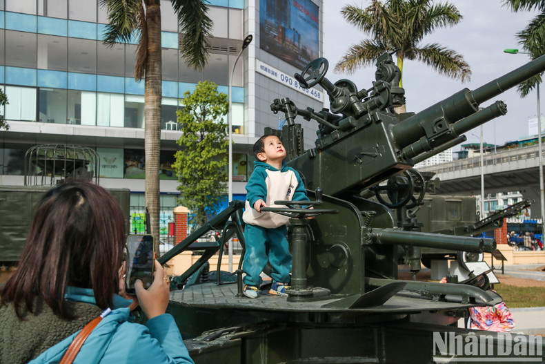 A mother takes a photo of her son pretending to control anti-aircraft artillery.