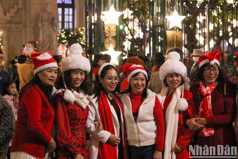 A group of women wearing red Santa Claus hats poses for a photo outside the entrance of Ham Long Church in Hoan Kiem District, Hanoi. (Photo: Nhat Quang)