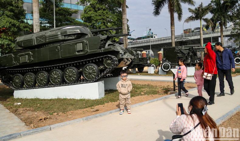 A boy standing in front of a tank on display at the museum.