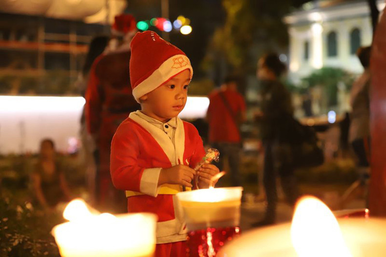 A boy dressed in a Santa Claus costume stands in front of Notre Dame Cathedral in District 1, Ho Chi Minh City. (Photo: The Anh)