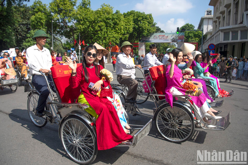 An Ao dai parade with flower-decorated cyclos moves along the Ly Thai To Monument. An Ao dai parade with flower-decorated cyclos moves along the Ly Thai To Monument.