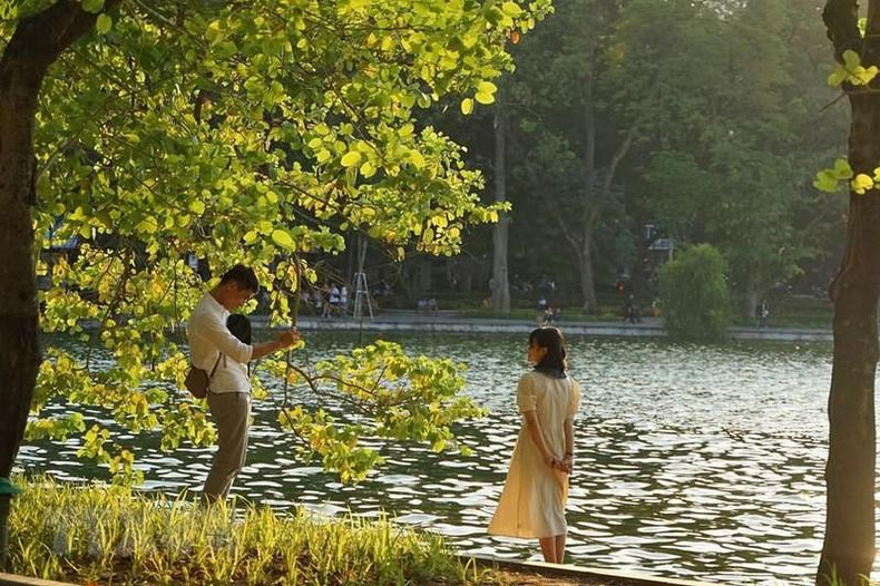 Young people save the autumn moment in Hanoi at Hoan Kiem Lake. (Photo: Khanh Hoa/VNA)