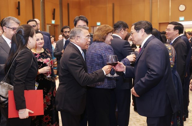 PM Pham Minh Chinh (R) and a foreign diplomat toast at the event. (Photo: VNA)