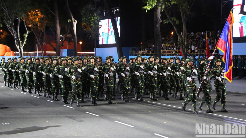 The Lao People's Army, in combat uniforms, march in formation, showcasing the deep solidarity and close ties between Vietnam and Laos in the journey of peacekeeping and development.