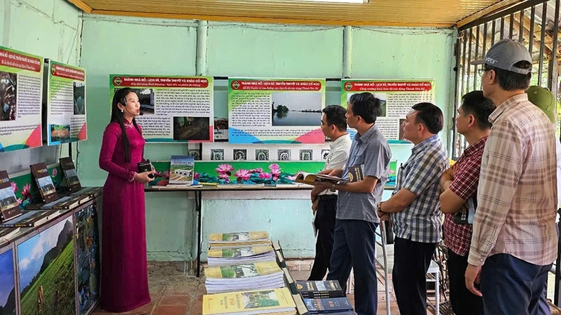 Journalists and reporters listen to a guide explain archaeological findings and the cultural space of Tay Do.