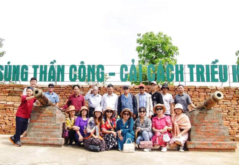Visitors take commemorative photos next to the Ho Dynasty cannon model.