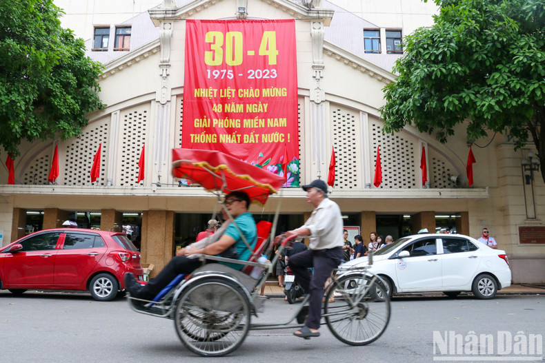 A large-format poster celebrating National Reunification Day is hung at Dong Xuan Market.