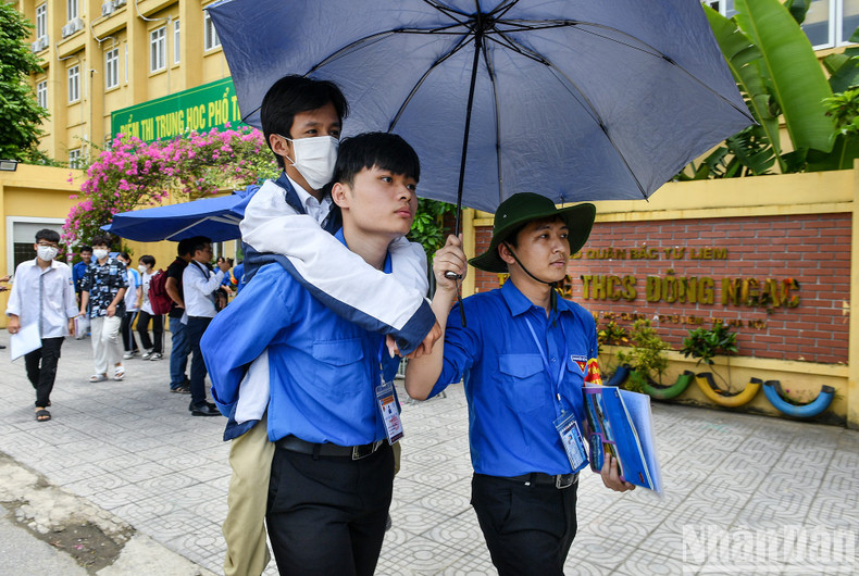 At the test venue at Dong Ngac Secondary School in Bac Tu Liem District, Hanoi, candidate Nguyen Huu Chinh, who suffers from “glass bone” disease, was carried on the back of a youth volunteer to enter the test room. At the test venue at Dong Ngac Secondary School in Bac Tu Liem District, Hanoi, candidate Nguyen Huu Chinh, who suffers from “glass bone” disease, was carried on the back of a youth volunteer to enter the test room.