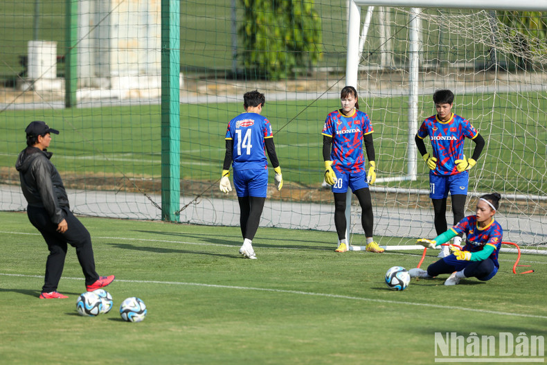 Goalkeepers do sets of exercises under the instruction of an assistant coach.