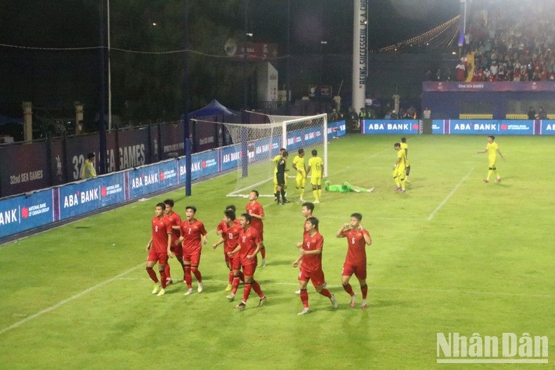 Vietnamese football players celebrate after a goal amidst the cheers of thousands of spectators. Vietnamese football players celebrate after a goal amidst the cheers of thousands of spectators.