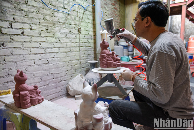Artisan Vuong The Cuong working on a cat pottery product.