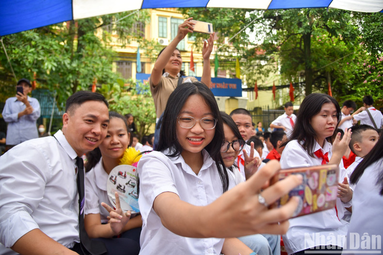 A school girl takes a selfie photo with her friends during the new academic year opening ceremony.