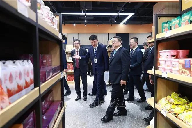 Prime Minister Pham Minh Chinh visits the booths selling Vietnamese products at the Chongqing International Logistics Hub Park. (Photo: VNA)