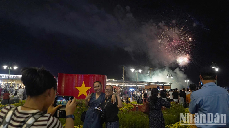 Many people excitedly use their phones to record the fireworks shining brightly in the city sky.