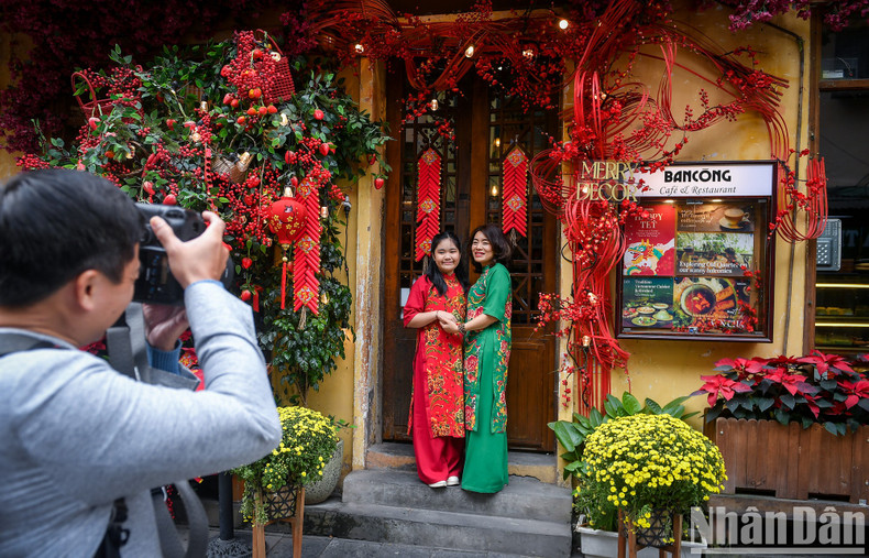 Mother and daughter pose in front of a cafeteria beautifully decorated with flowers to welcome Tet 2024.