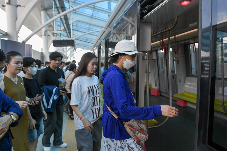 People queue in line to experience the metro line on its first day of operation.