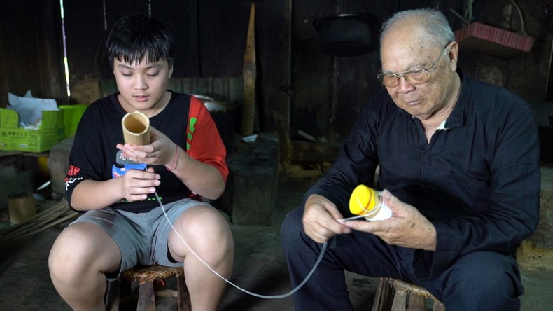 Lo Van Chien teaches his descendant the technique of making singing tubes for ‘hat ong’ singing Lo Van Chien teaches his descendant the technique of making singing tubes for ‘hat ong’ singing