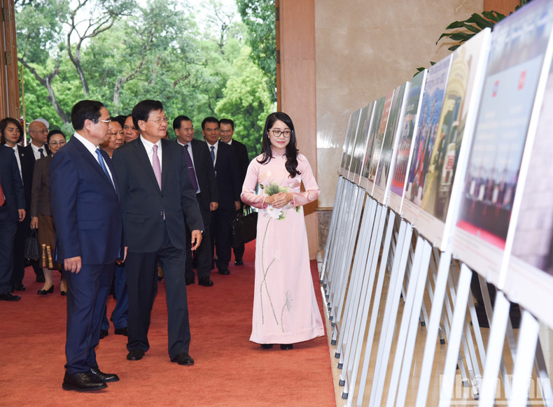 Prime Minister Pham Minh Chinh and Party General Secretary and President of Laos Thongloun Sisoulith admire photos on the outcomes of diplomatic ties between the two countries.