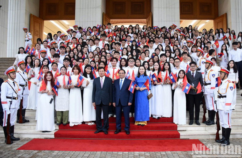 Prime Minister Pham Minh Chinh and Party General Secretary and President of Laos Thongloun Sisoulith pose for a group photo with lecturers and students of the Vietnam National University.
