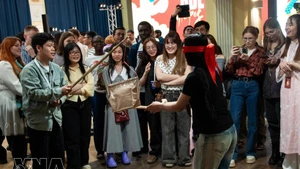 Young participants from India, Indonesia and Russia learn about the traditional pot-breaking game. (Photo: VNA)