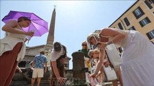 People collect drinking water to cool down on a hot day in Rome, Italy. (Photo: Xinhua/VNA)