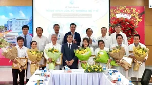 Deputy Minister of Health Tran Van Thuan presents flowers and certificates of merit to the team who performed the fetal intervention for the Singaporean mother. (Photo: HOANG HUNG)