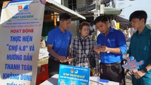 Youth union members guide vendors on cashless payments at My Ngai Market, Ward 1, Cao Lanh City.