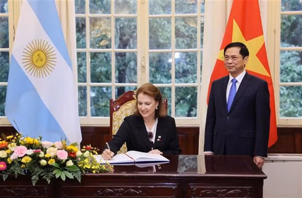 Argentina’s Minister of Foreign Affairs, International Trade and Worship Diana Elena Mondino writes in a guestbook in the witness of Foreign Minister Bui Thanh Son. (Photo: VNA)
