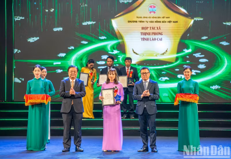 Minister of Agriculture and Rural Development Le Minh Hoan and Editor-in-Chief of Nhan Dan Newspaper Le Quoc Minh present the logo and certificate to outstanding agricultural cooperatives.