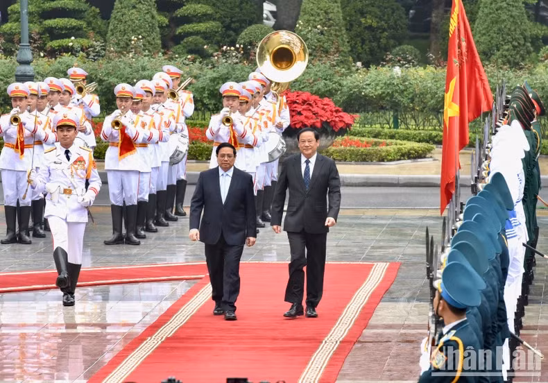 PM Pham Minh Chinh (L) and his Lao counterpart Sonexay Siphandone review the guard of honour at the welcome ceremony in Hanoi on January 6 morning.