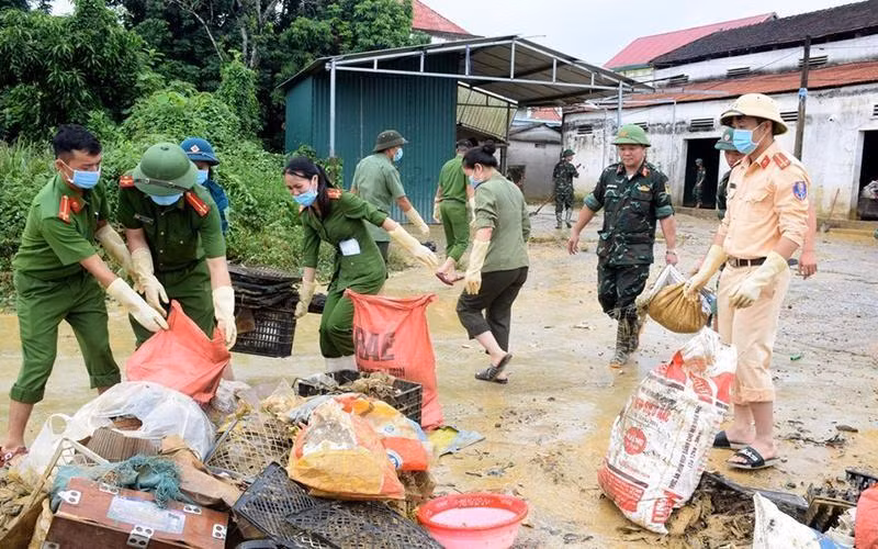 Police force and army soldiers clear a flooded street caused by heavy rains in Thanh My commune, Thanh Chuong district, Nghe An province (Photo: Xuan Hoang)
