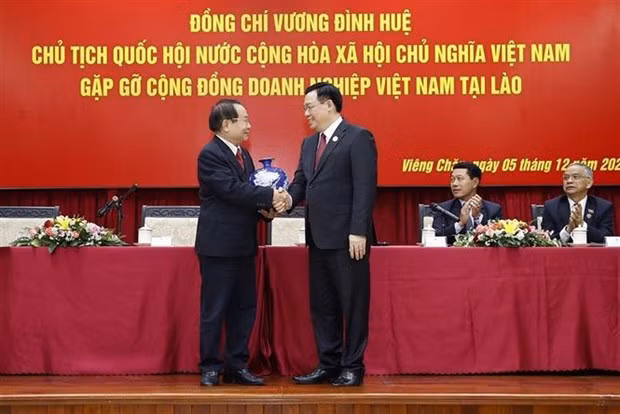 NA Chairman Vuong Dinh Hue (R) shakes hands with a representative of Vietnamese enterprises in Laos. (Photo: VNA)