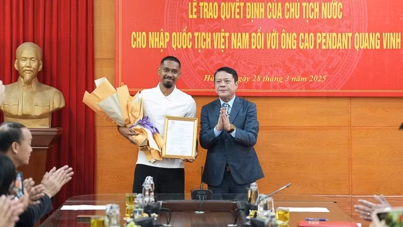 Representative of Hanoi Department of Justice presents the Vietnamese nationality certificate to football player Cao Pendant Quang Vinh. (Photo: PHAN THACH)
