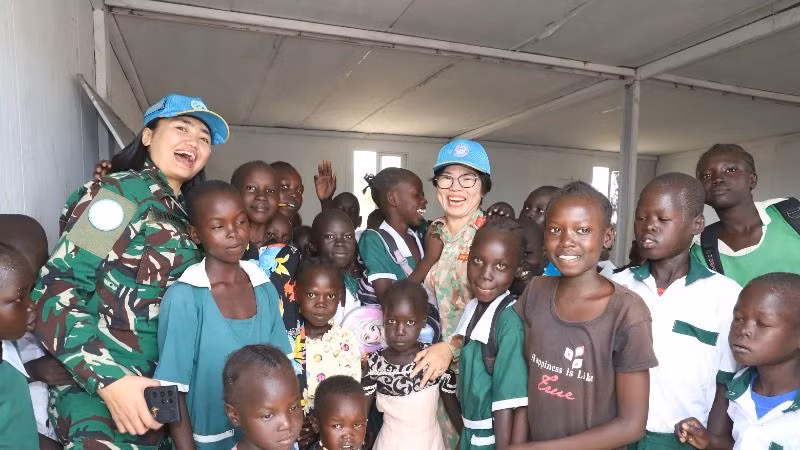 Head of Civil-Military Coordination Office at UNISFA takes a souvenir photo with students of Abyei Primary School.