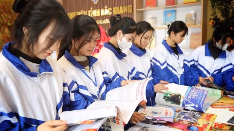 Pupils reading books at an exhibition booth celebrating the 50th anniversary of the Liberation of the South and National Reunification at Bac Giang Library.